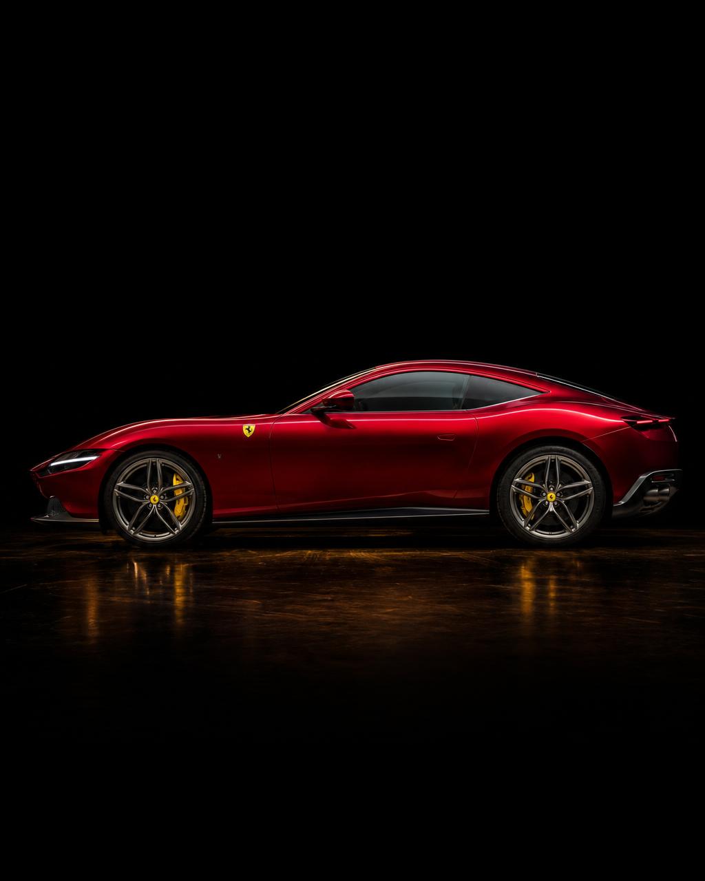 Ferrari Roma in deep red with gold brake calipers in dark studio